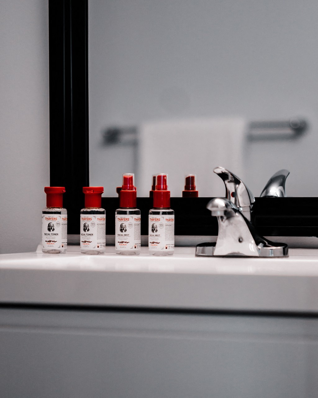 four bottles of cosmetics sitting on top of a bathroom sink