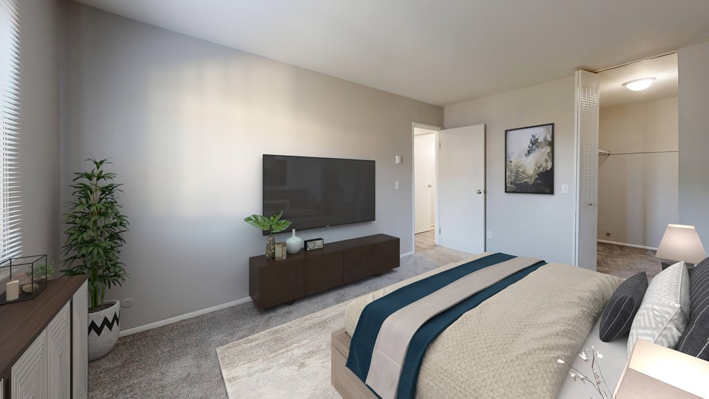 A bedroom with a bed, a television, and a plant.