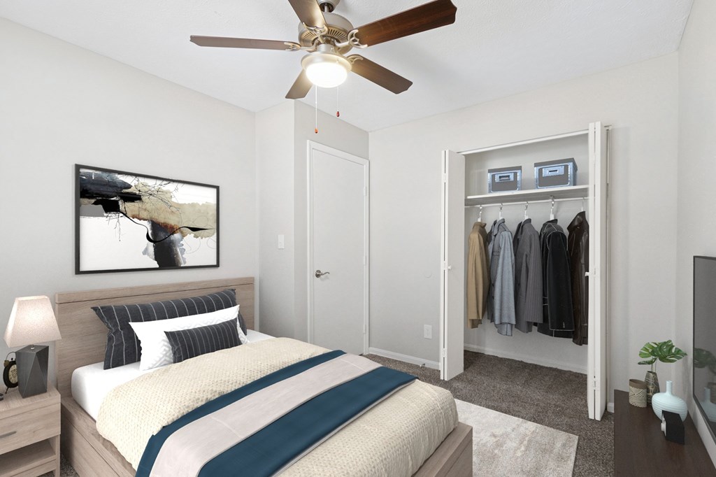 A bedroom with a bed, a ceiling fan, and a closet.
