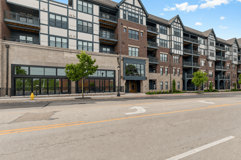 A street view of a row of apartment buildings with a tree in front of the first one.