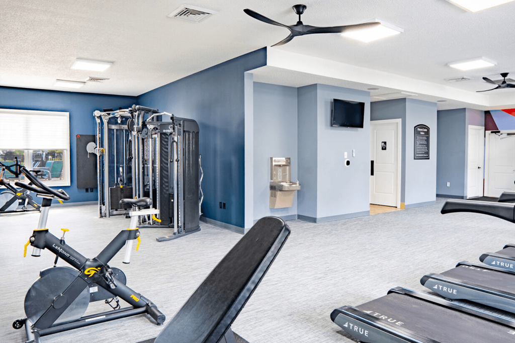 Gym with weights and cardio machines and a wall mounted tv