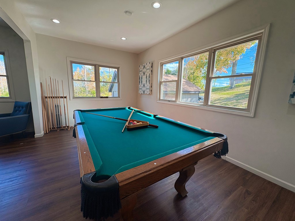 A pool table in a room with a view of the backyard.