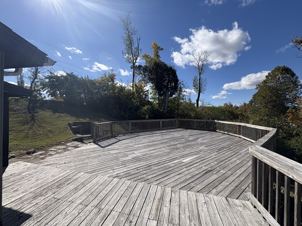 A wooden deck overlooks a grassy area with trees.