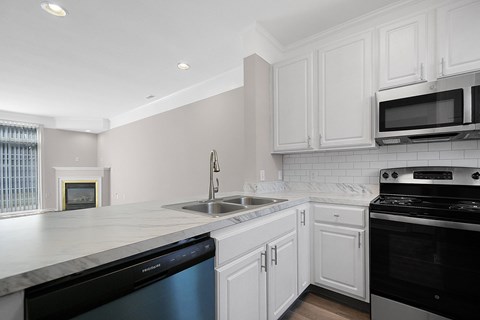 A kitchen with white cabinets and black appliances.