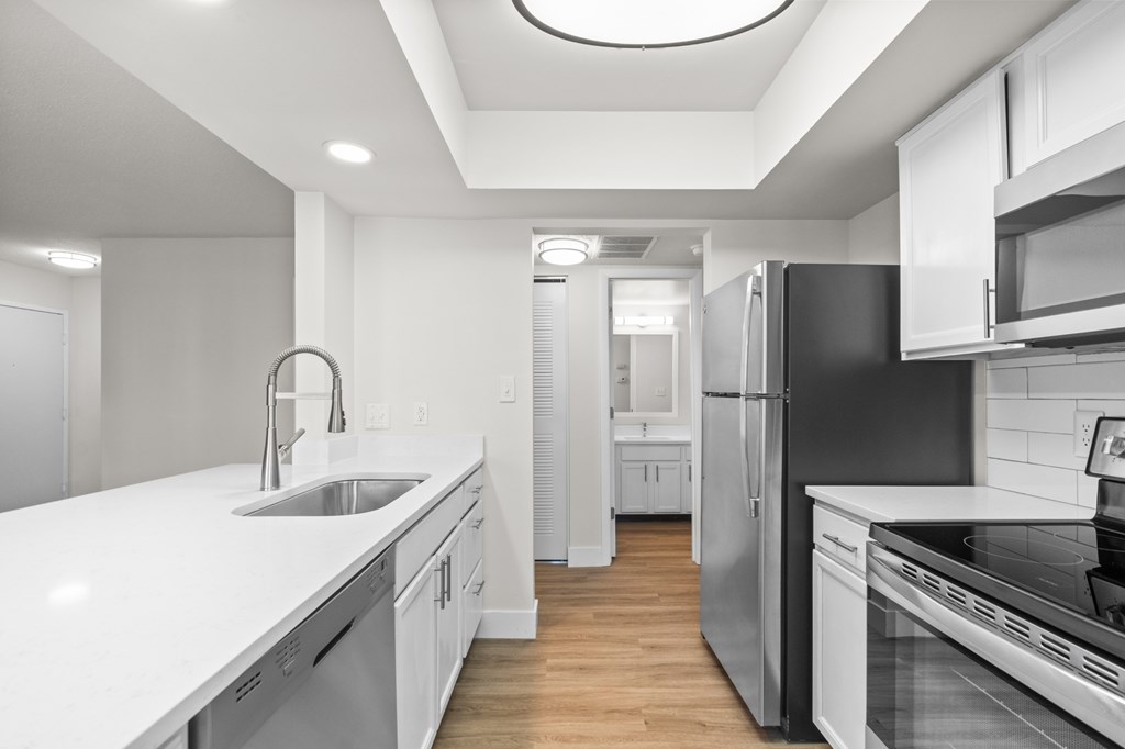 A modern kitchen with white cabinets and stainless steel appliances.