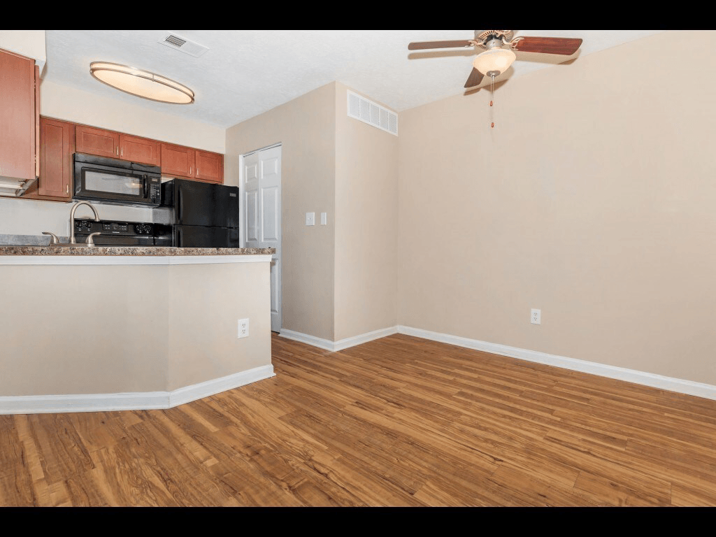 A kitchen with wooden floors and a ceiling fan.