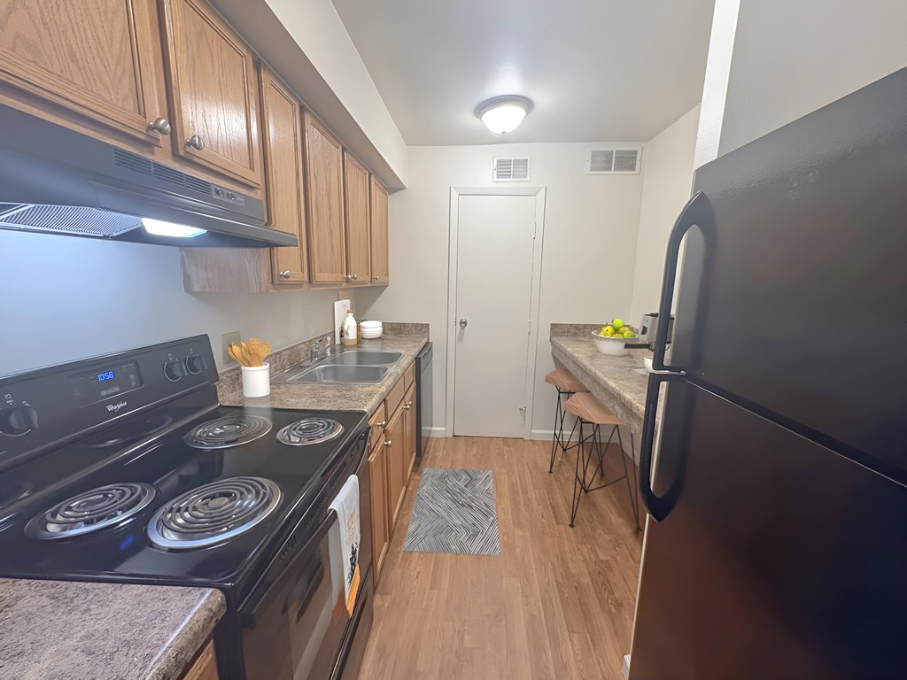A kitchen with a black stove top oven and a black refrigerator.