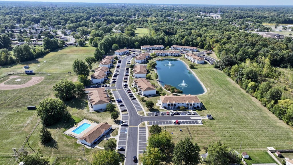 A bird's eye view of a residential area with a lake and a swimming pool.