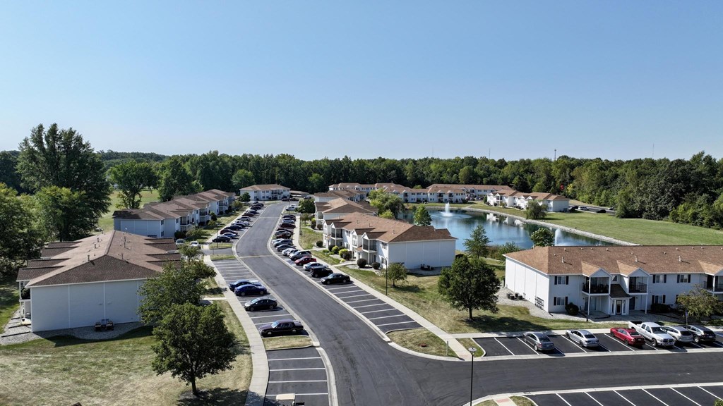 A sunny day at a residential complex with a pond and greenery.