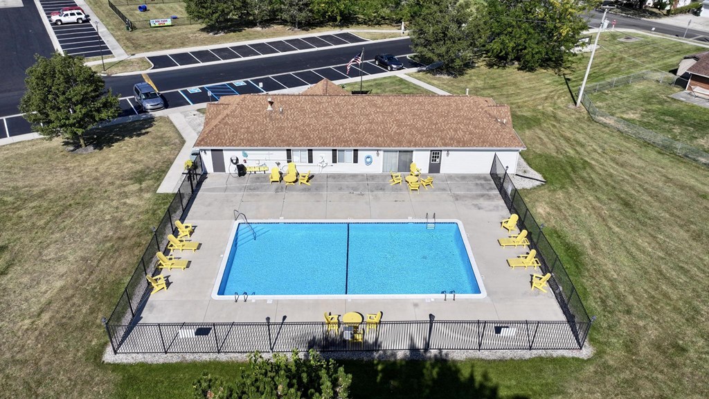 An aerial view of a pool with yellow lifeguard chairs and a building with a red roof.