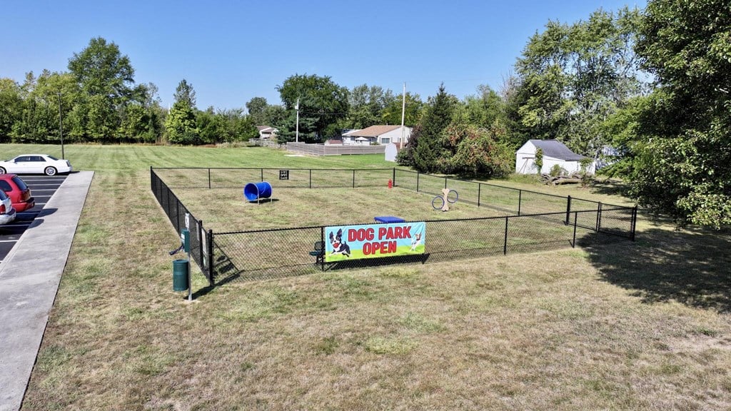 A sign that says Dog Park Open is on a fence.