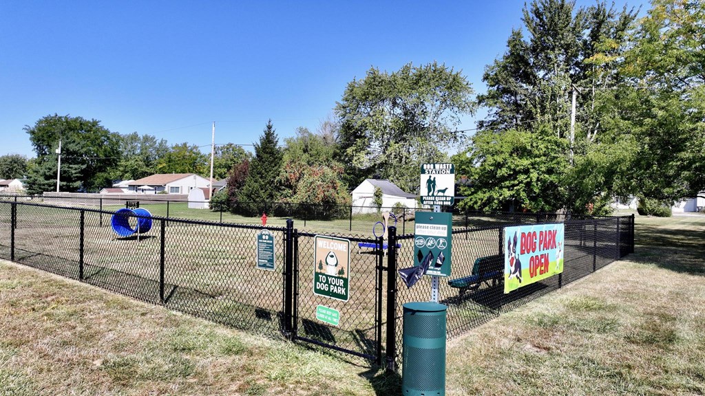 A sign in front of a fence advertises a dog park.