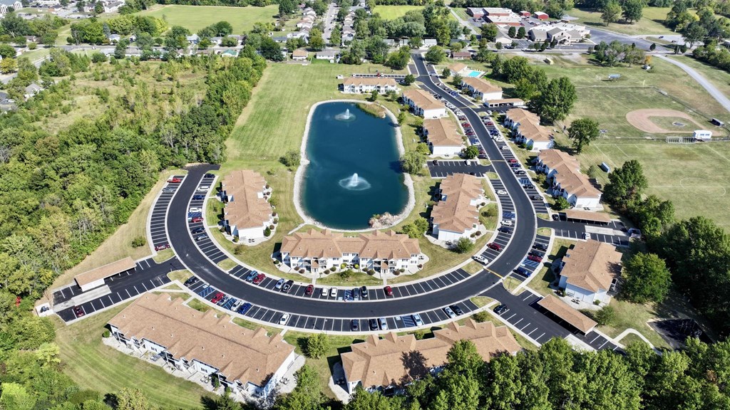 A bird's eye view of a roundabout with a lake in the middle of a residential area.