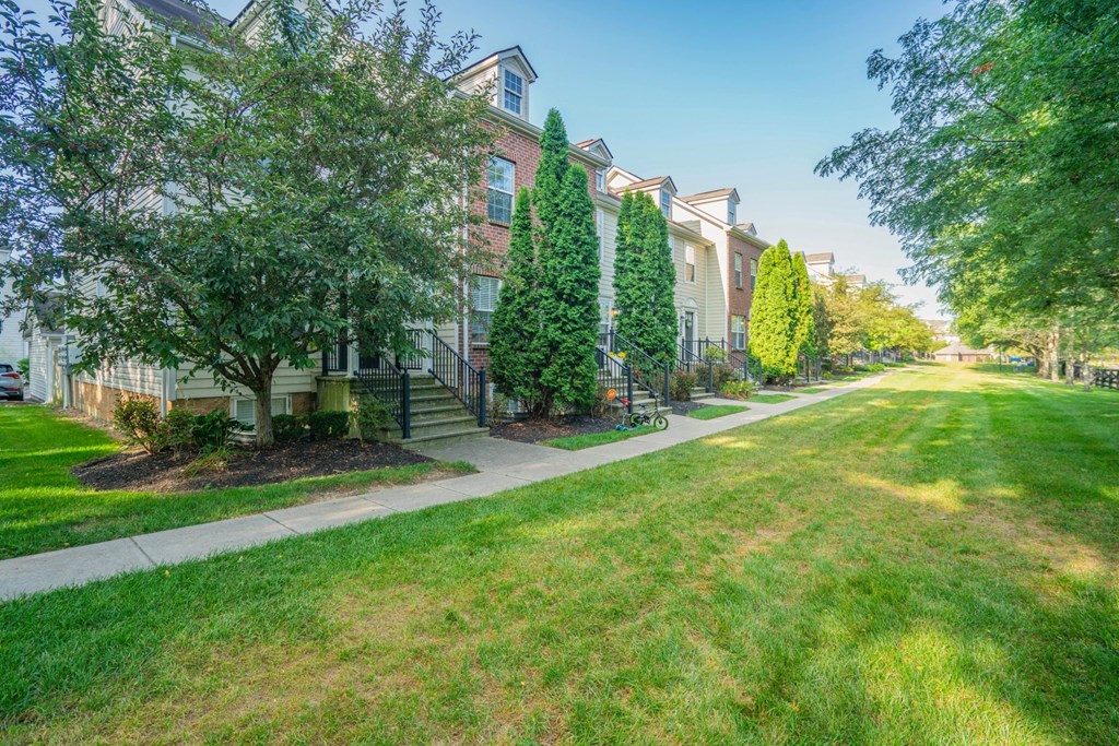 exterior view of a brick apartment building with green grass and trees at Traditions at Slate Ridge, Reynoldsburg Ohio