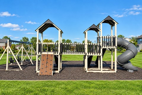 A playground with a slide, swings, and a wooden structure.