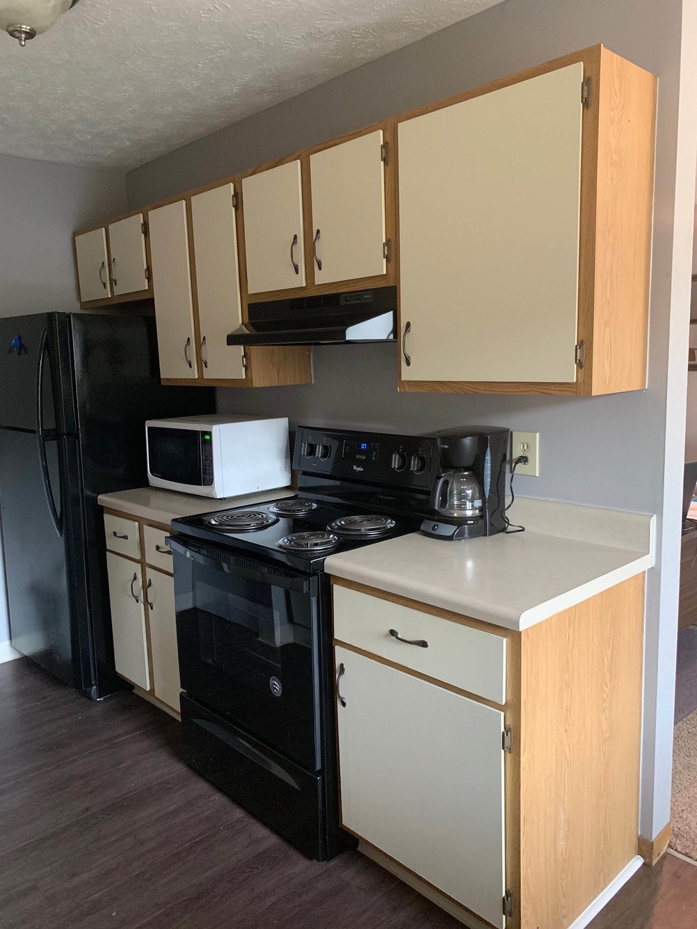 A kitchen with a black refrigerator, white oven, and wooden cabinets.