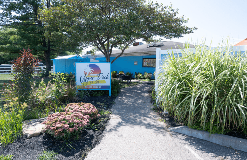 a path leading to a blue building with a sign