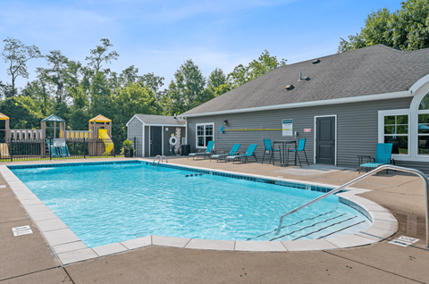 our resort style swimming pool is in front of our apartments with chairs and a house