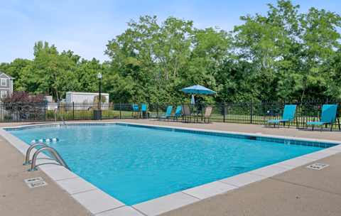 a swimming pool with blue chairs and a fence around it