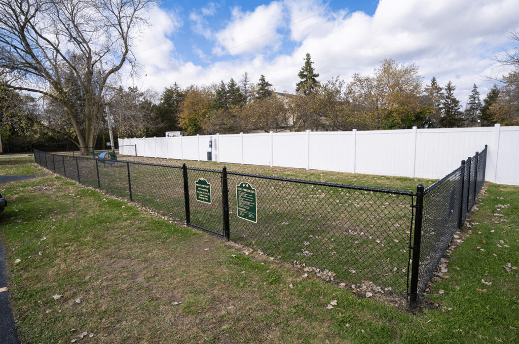 a chain link fence with two signs on it in a field