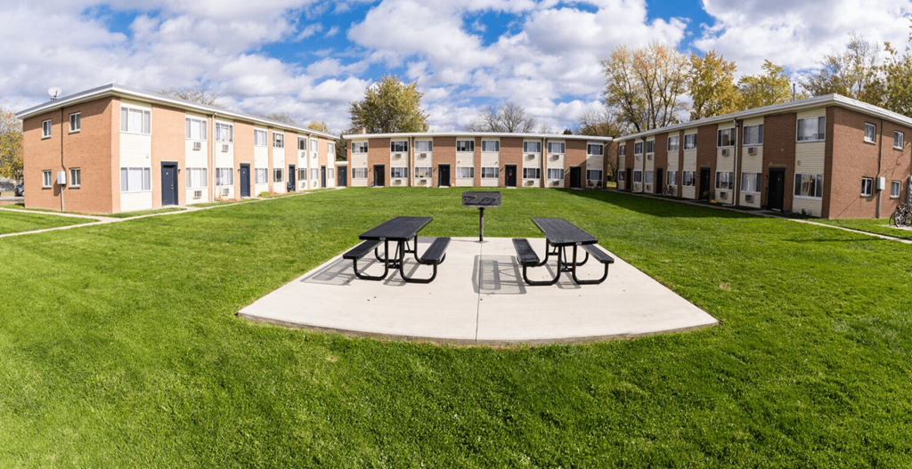 a courtyard with picnic tables in front of an apartment building