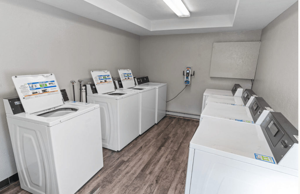 a laundry room with four washers and dryers and a row of washing machines