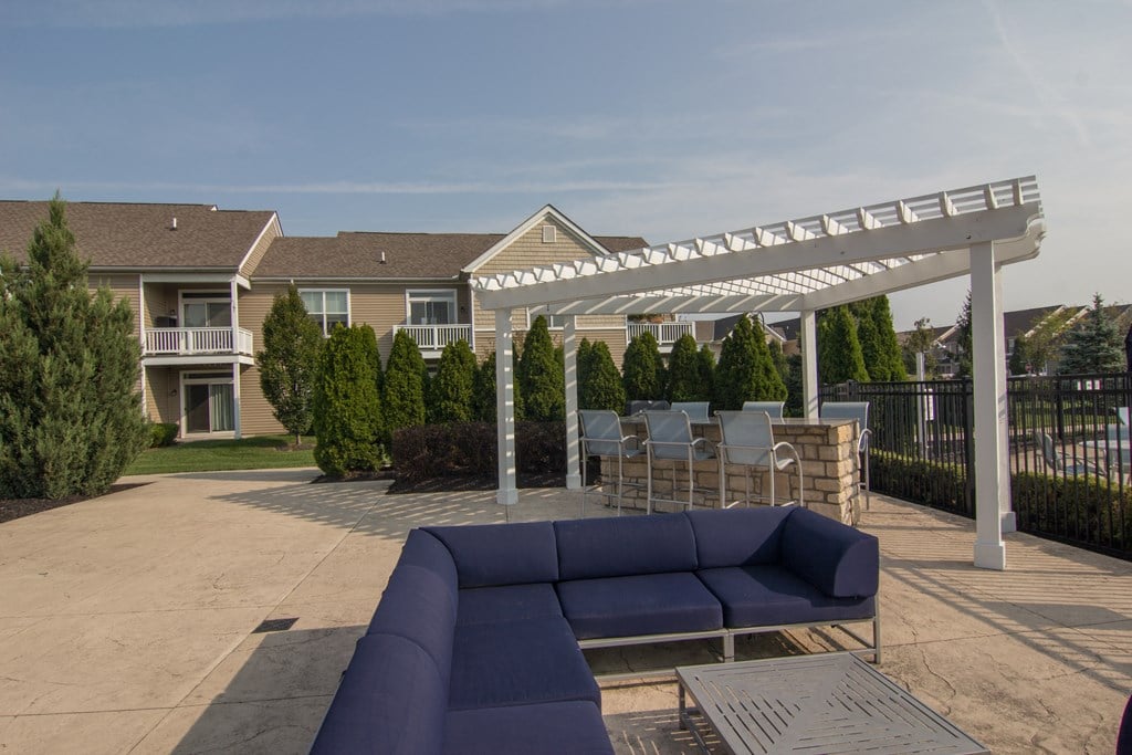 a patio with a couch and a table under a white pergola  at Grove City Summit, Ohio