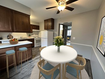 a dining area with a white table and four chairs and a kitchen in the background - Photo Gallery 8