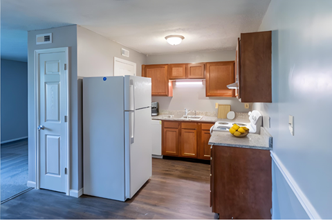 a kitchen with a white refrigerator and wooden cabinets at Crossings of Kenton, Kentucky, 41018