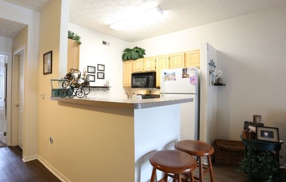 A kitchen with a white refrigerator and wooden stools.at The Cove, Columbus, 43110