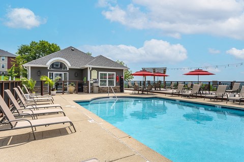 Outdoor pool with lounge chairs and umbrellas at Hilltop Apartments, Cincinnati