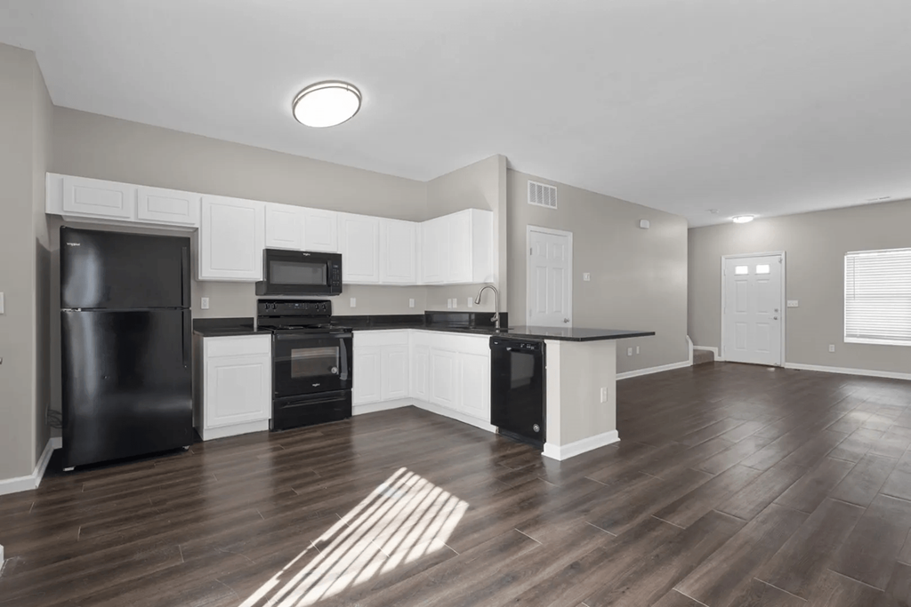 an empty kitchen with black appliances and white cabinets at Traditions at Slate Ridge, Ohio