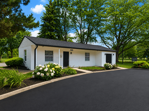 A white house with a black roof and a driveway in front.