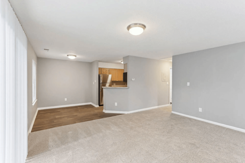A spacious room with a carpeted floor and a wooden cabinet.