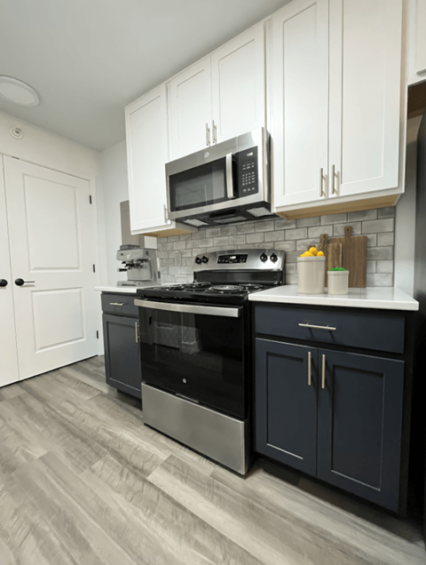 a kitchen with white cabinets and black appliances and a microwave