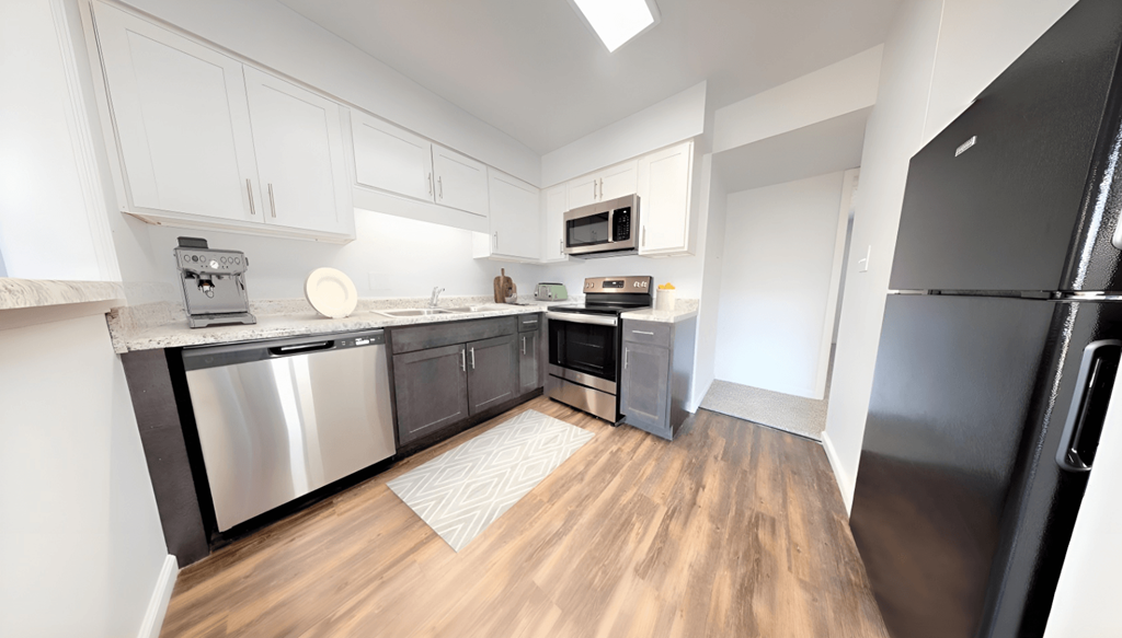 an empty kitchen with stainless steel appliances and white cabinets