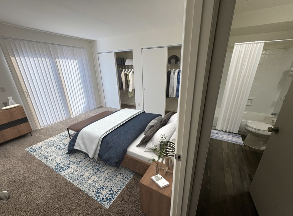 A bedroom with a bed, a nightstand, and a window with blinds.