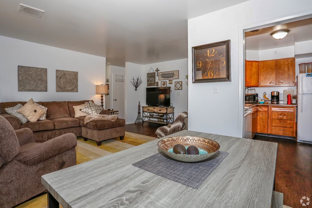 A living room with a grey coffee table and brown couches.