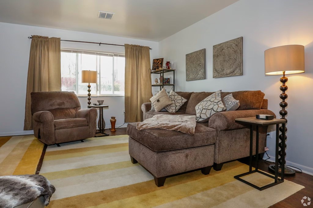 A living room with a brown couch, a chair, and a lamp.