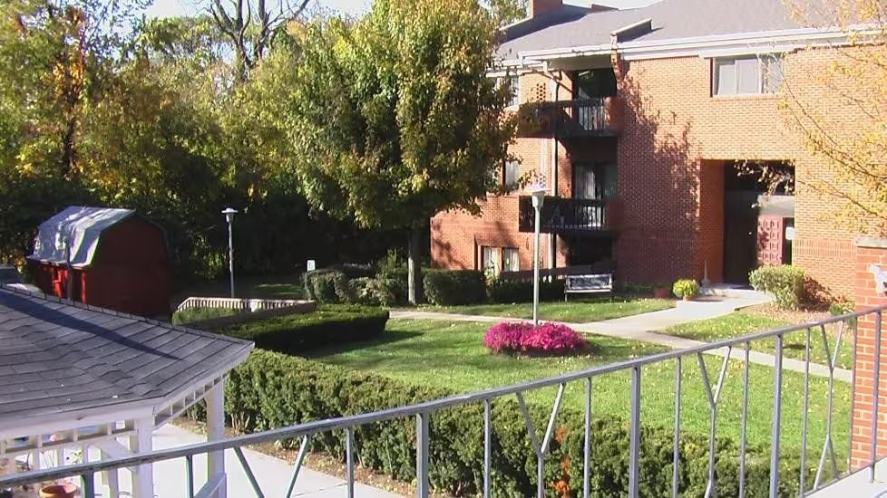 A red building with a white roof is in the background of a green lawn.