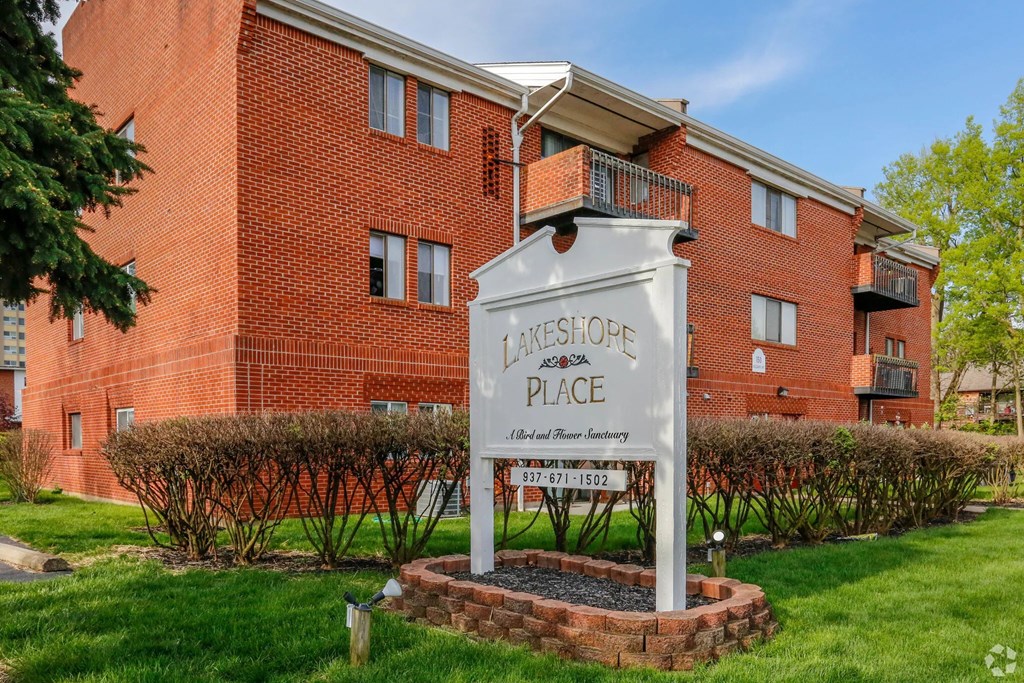 A sign for a place called "Lakeshore Place" stands in front of a red brick building.