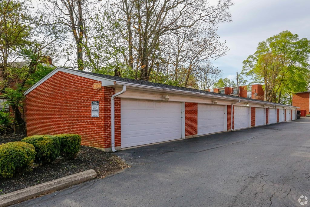 A red brick building with white garage doors in front of a tree.