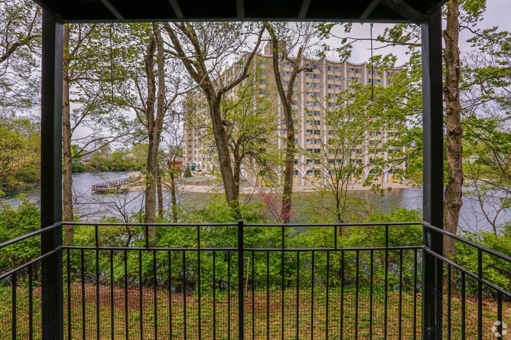 A view of a river through a fence with trees in the foreground.