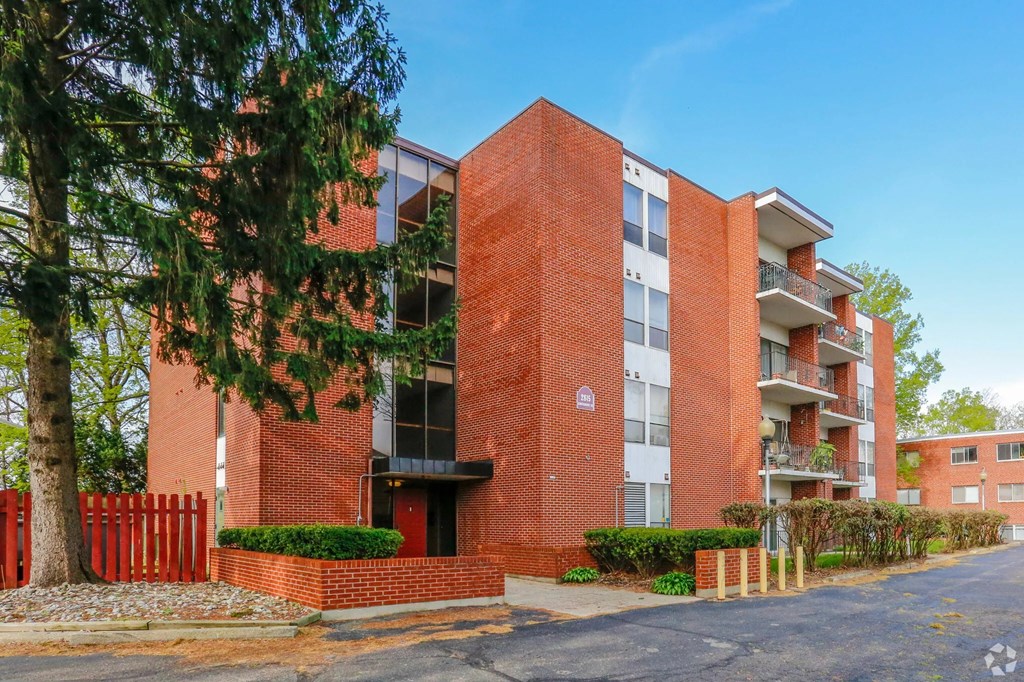 A red brick apartment building with a tree in front.