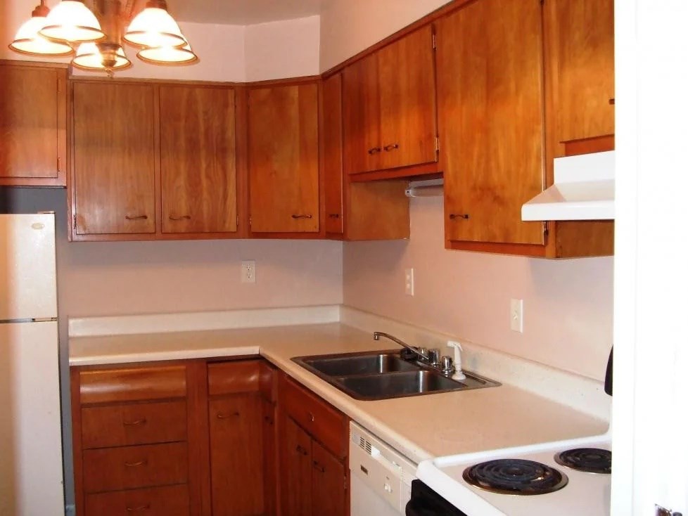A kitchen with wooden cabinets and a white stove top oven.