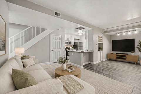 A modern living room with a staircase on the left and a television on the right.