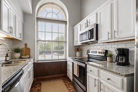A kitchen with white cabinets and a black stove top oven.
