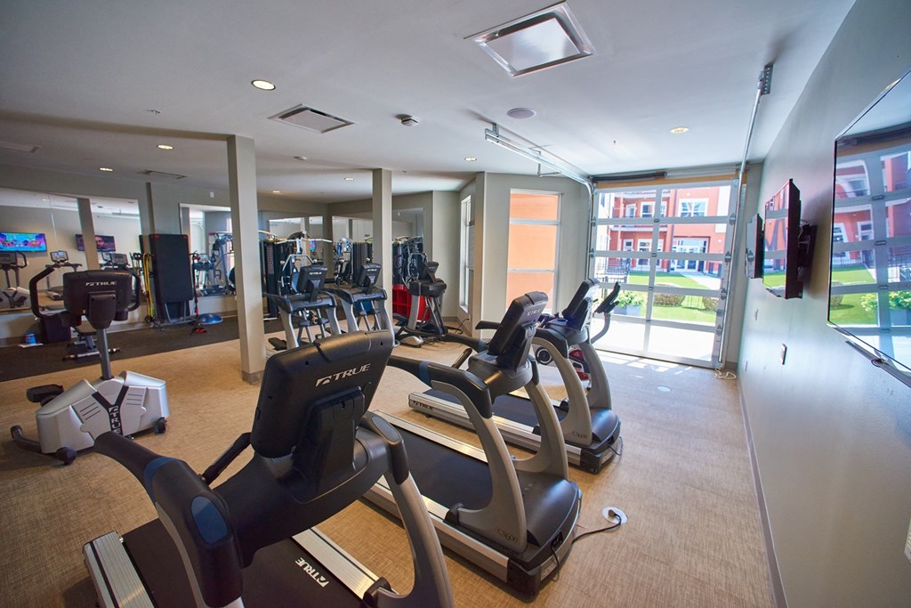 Apartments in West Chester for Rent- Liberty Center- Fitness Center with Treadmills, Floor-to-Ceiling Windows, and Mounted Televisions