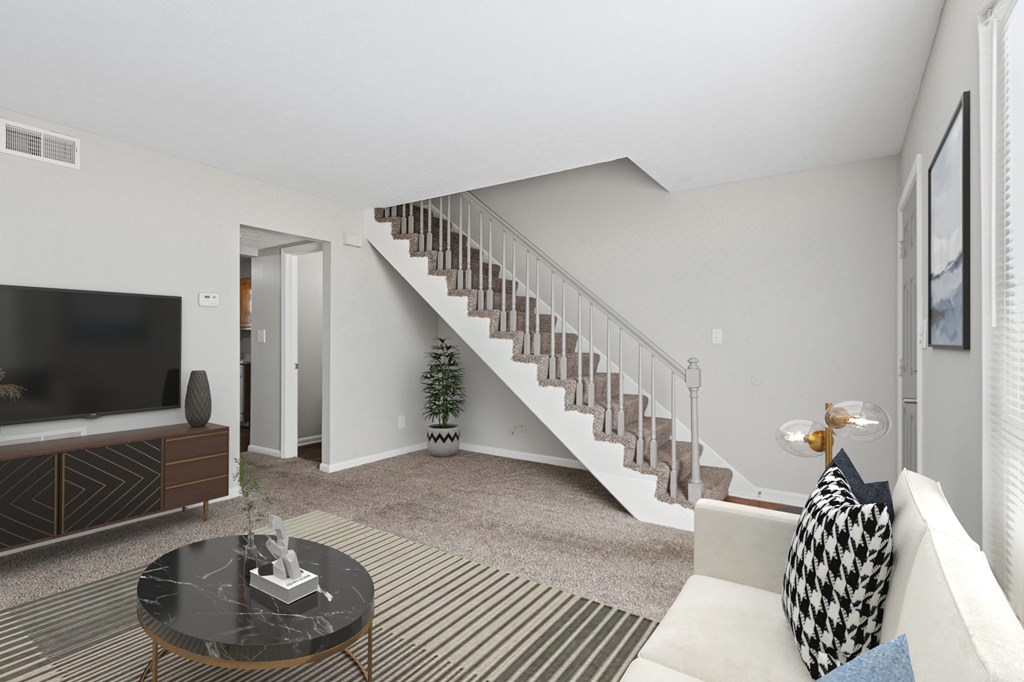 A living room with a staircase in the background.