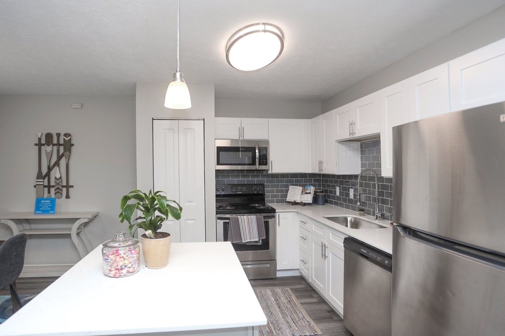 A kitchen with a white table and stainless steel appliances.